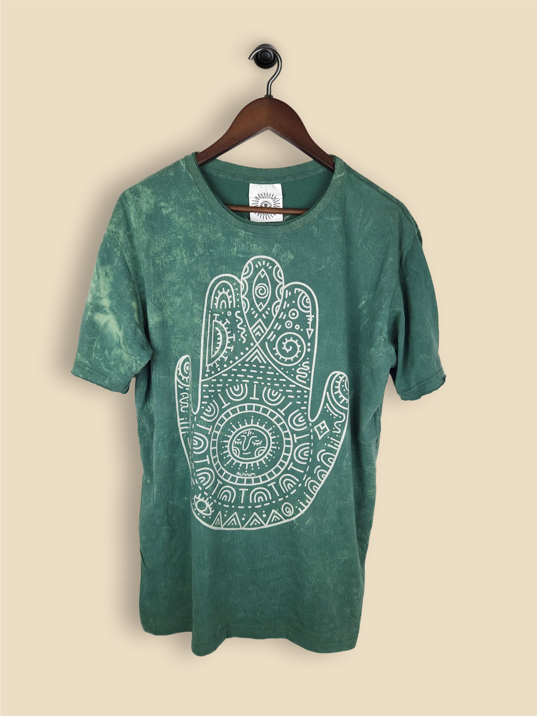 A green t-shirt featuring a print of a hamsa hand with geometric patterning