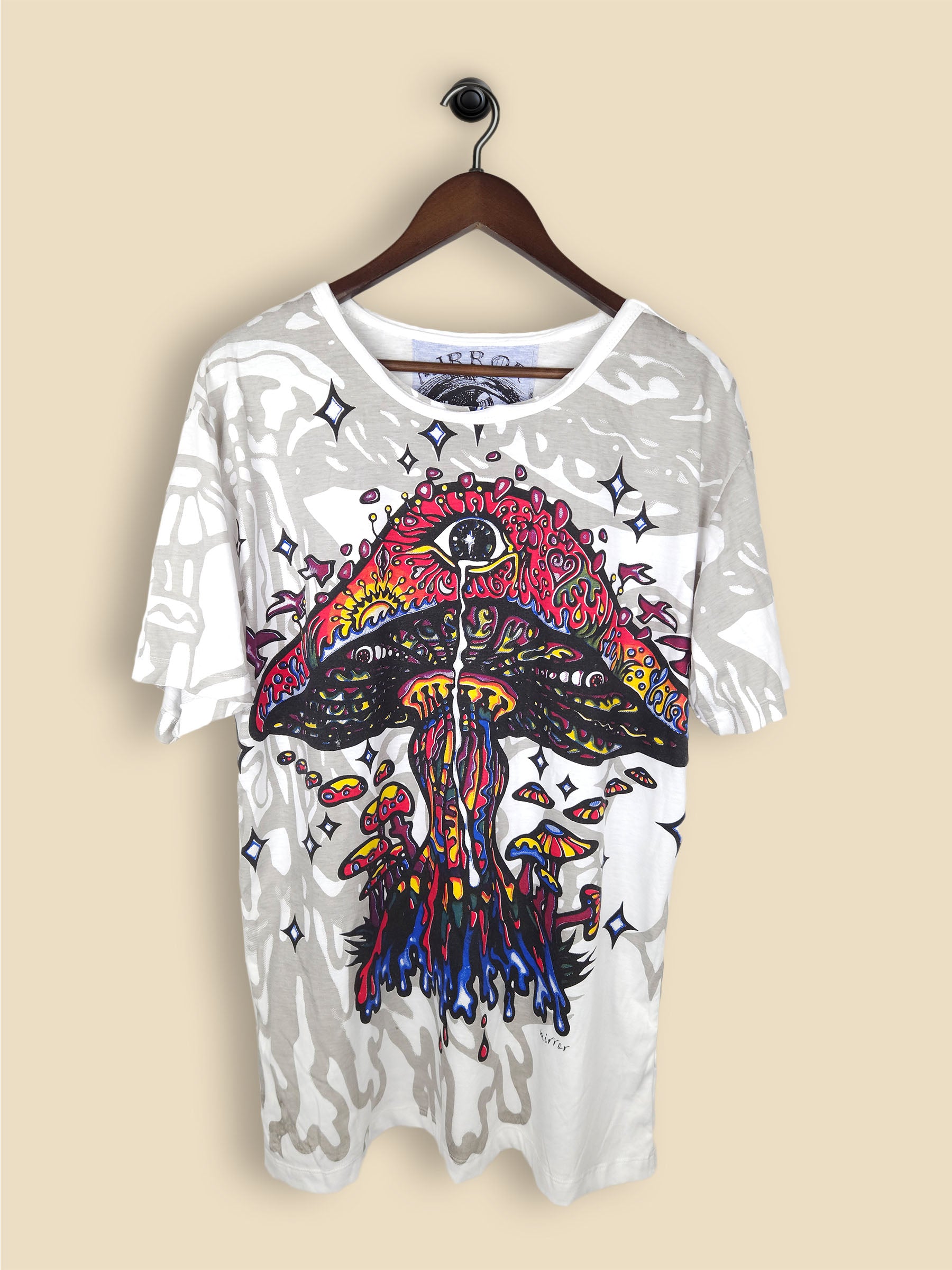 A white T-shirt featuring a colourful, psychedelic mushroom design with smaller mushrooms, vibrant colours and star-like shapes.