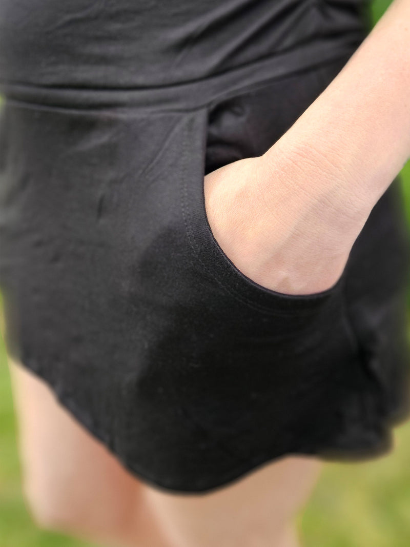 Person wearing a black dress with a cutout design on a grassy background