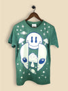 Green t-shirt featuring a bold alien face with large eyes, a mushroom detail on the forehead, and space-themed accents like stars and planets