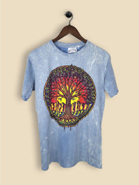 A light blue stonewashed T-shirt with a colourful tree of life design featuring a vibrant sunset