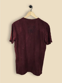 A maroon T-shirt with a colourful tree of life design featuring a vibrant sunset