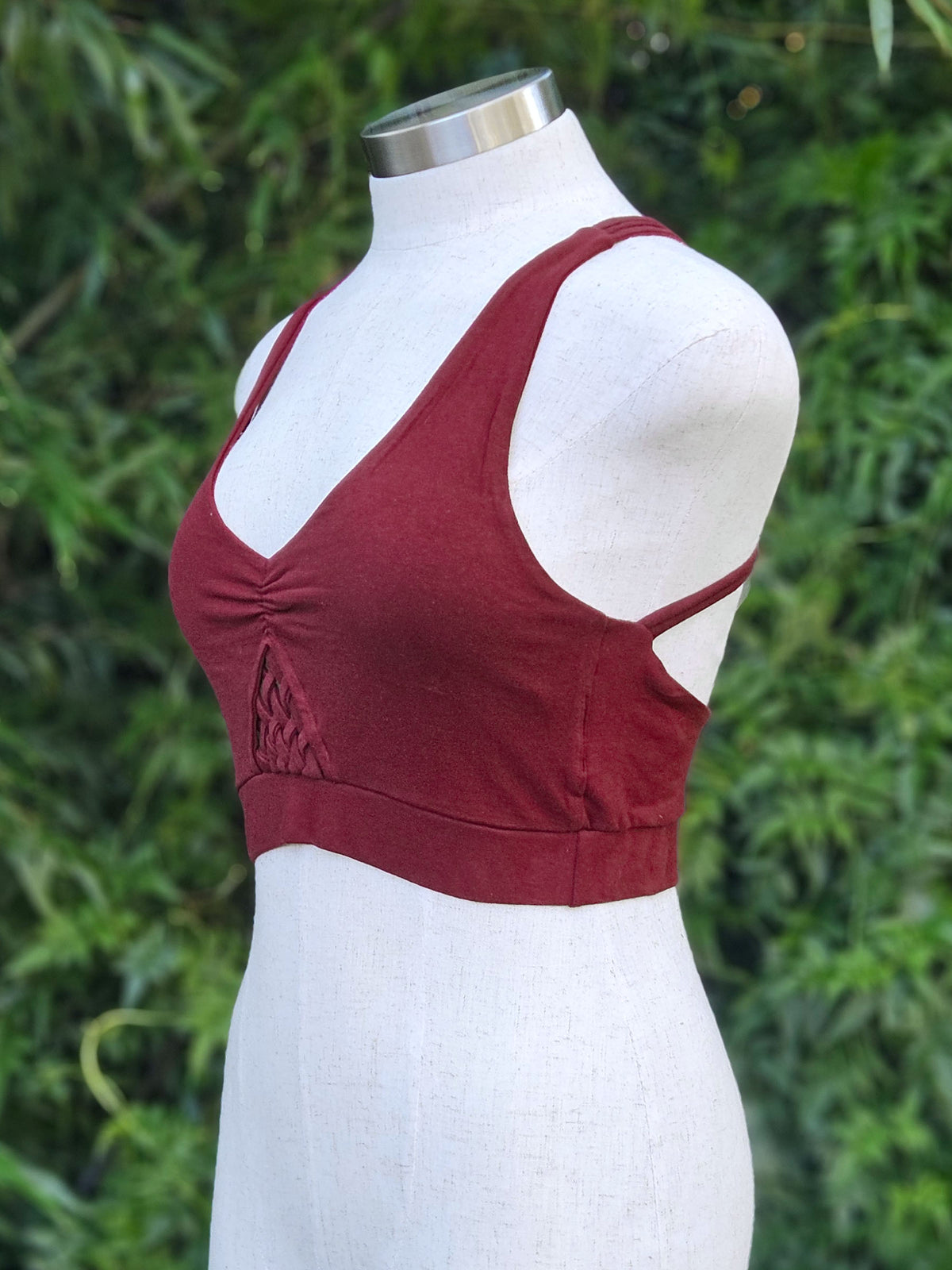 Maroon tank top on a mannequin against a green leafy background
