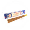 A blue rectangular box labeled 'Satya Sai Baba Nag Champa Agarbatti' with certifications and export quality markings is displayed with several brown incense sticks laid out in front. Incense powder is scattered around the sticks, highlighting the quality and traditional craftsmanship of the product.