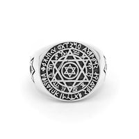 A silver ring featuring intricate designs and symbols. The central design is a hexagram (Star of David) surrounded by concentric circles filled with various symbols and characters. The outer circle contains a series of runic or mystical characters.