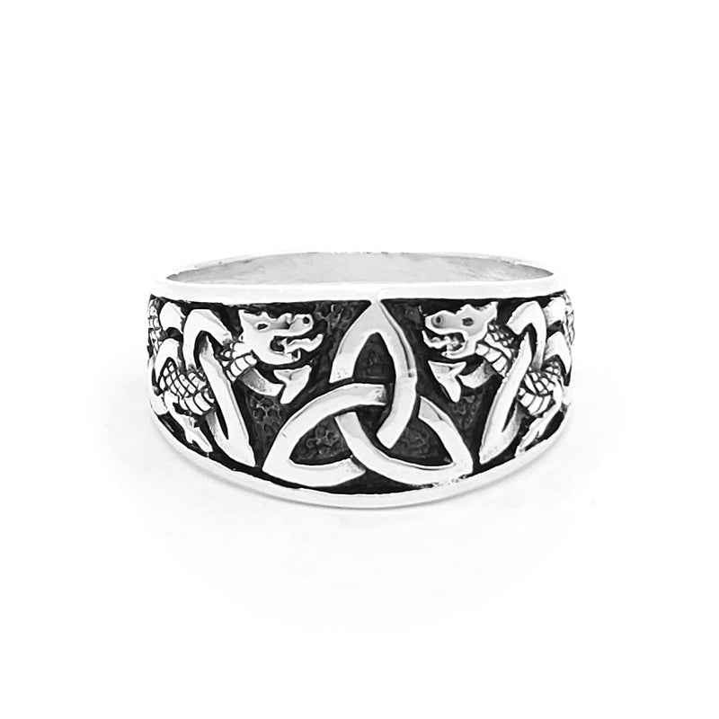 Silver dragon ring featuring two intricately carved dragon heads framing a Celtic triquetra knot. Darkened background enhances contrast, highlighting the detailed engravings.