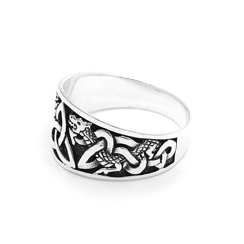Silver dragon ring featuring two intricately carved dragon heads framing a Celtic triquetra knot. Darkened background enhances contrast, highlighting the detailed engravings.