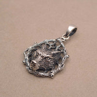 Side shot of sterling silver wolf face pendant in woodland surrounding
